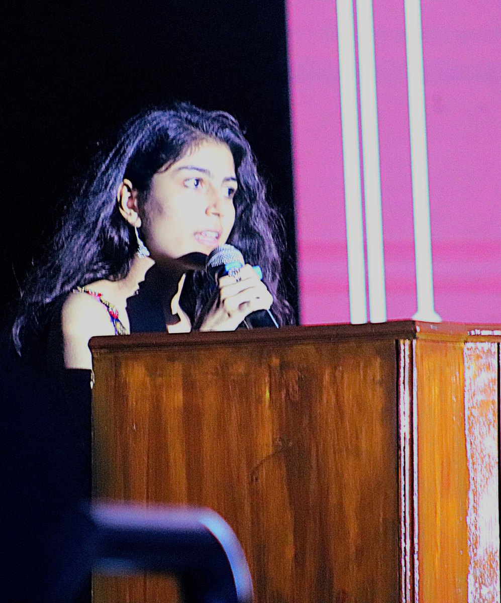Diya Nathwani speaking at a podium on stage